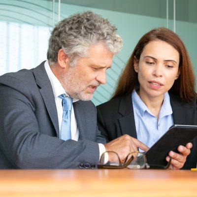 Businesswoman presenting project to investor Businesswoman presenting project to investor. Serious female employee showing content on tablet to colleague, explaining details. Communication or teamwork concept