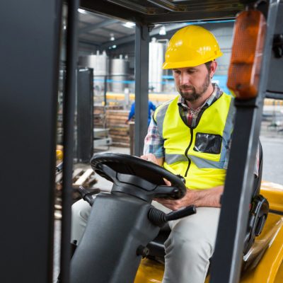 Young male worker sitting in forklift at warehouse Young male worker sitting in forklift at warehouse